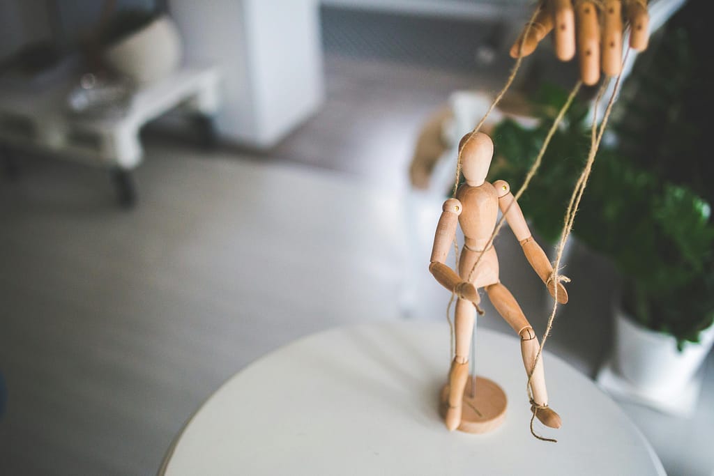 Wooden puppet on strings symbolising dependency and control within family relationships