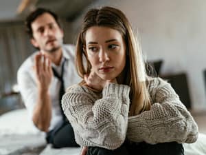 Woman looking away while partner speaks, showing emotional disconnection during conflict